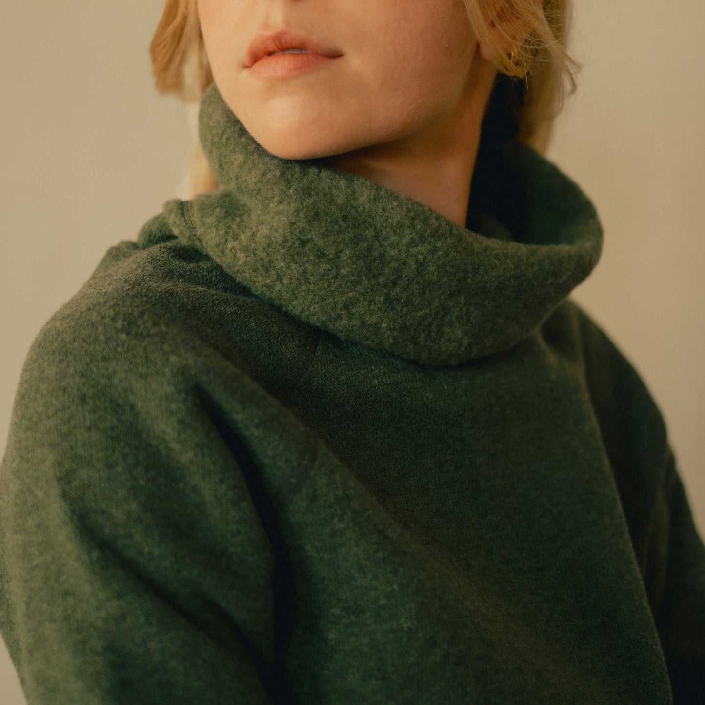 A woman wearing a green American made Duckworth merino wool fleece turtle neck. 