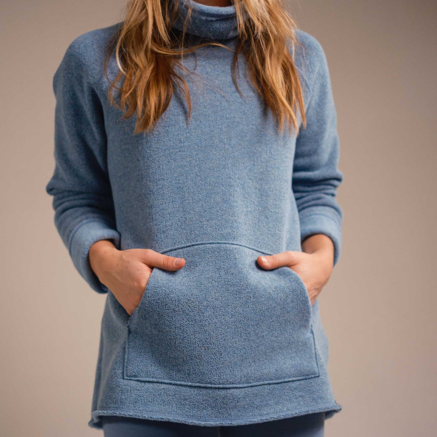 A woman wearing a blue American made Duckworth merino wool fleece turtle neck. 