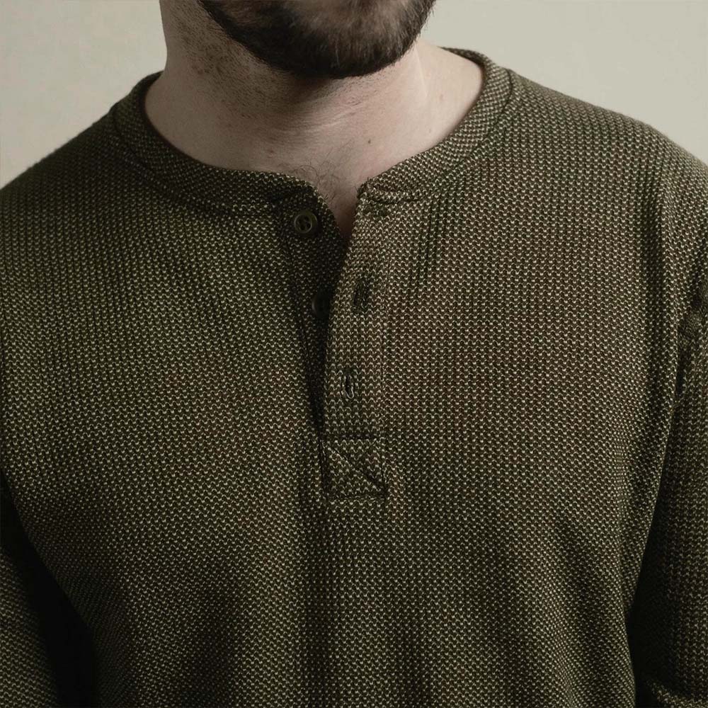 A man wearing a green American made Duckworth merino wool waffle knit long sleeve henley. 