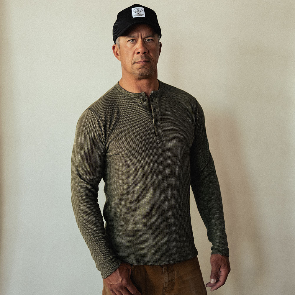 A man wearing a green American made Duckworth merino wool waffle knit long sleeve henley. 