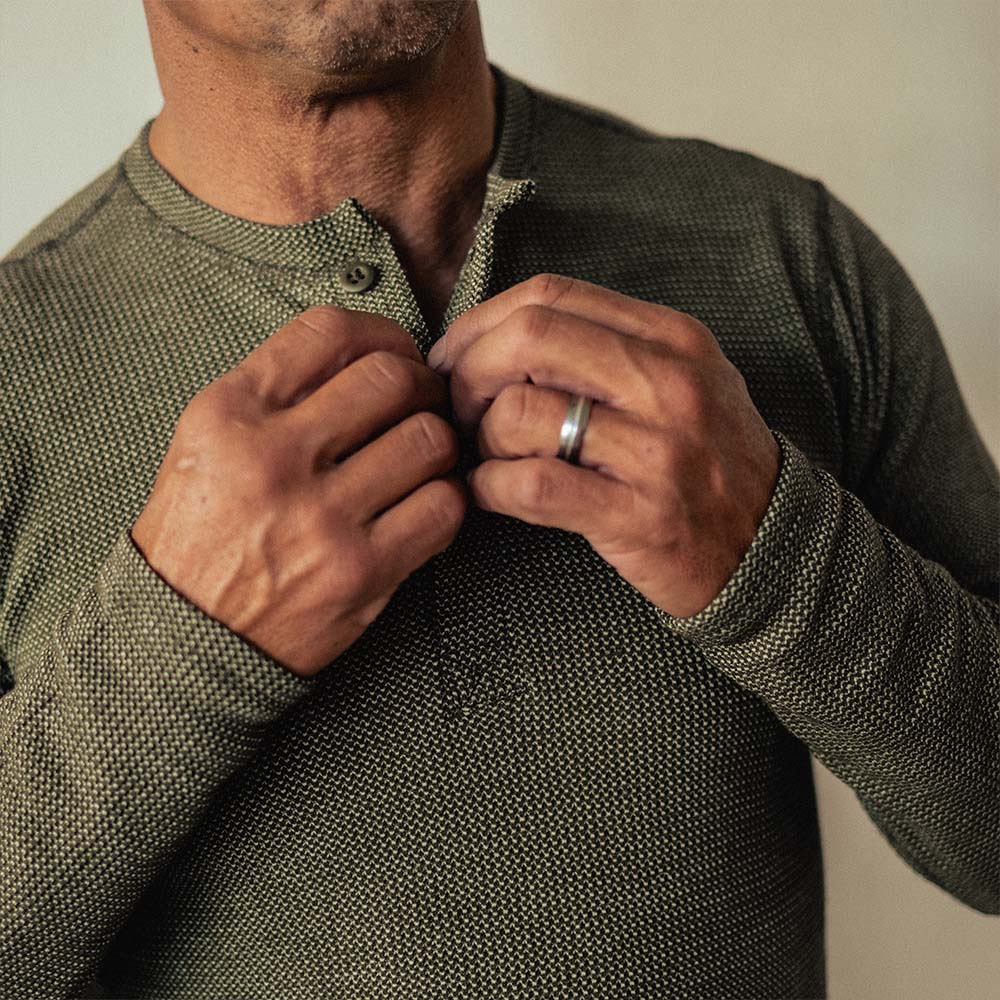 A man wearing a green American made Duckworth merino wool waffle knit long sleeve henley. 