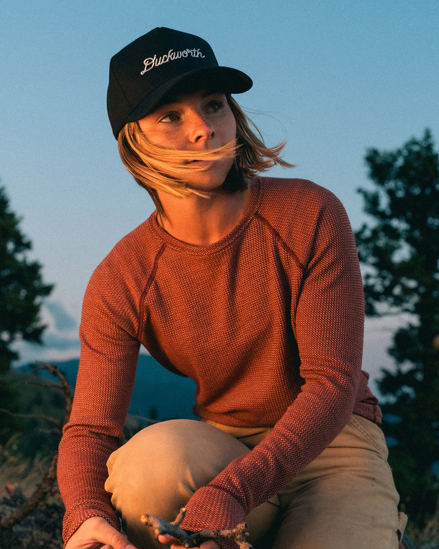 A woman camping in the mountains wearing a waffle kit merino wool layer.