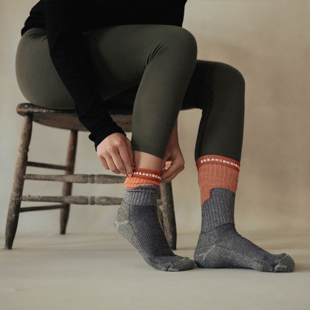 A woman wearing orange and gray midweight American made merino wool sock.