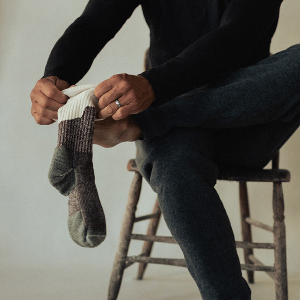 A man putting on a midweight American made merino wool sock.