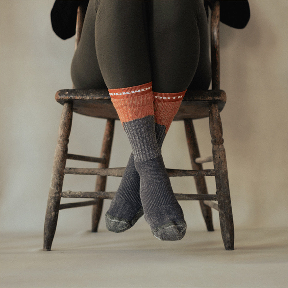 A woman wearing orange and gray midweight American made merino wool sock.