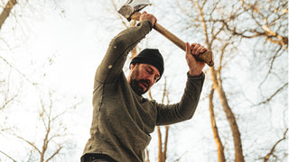 A man chopping wood in a merino waffle knit. 